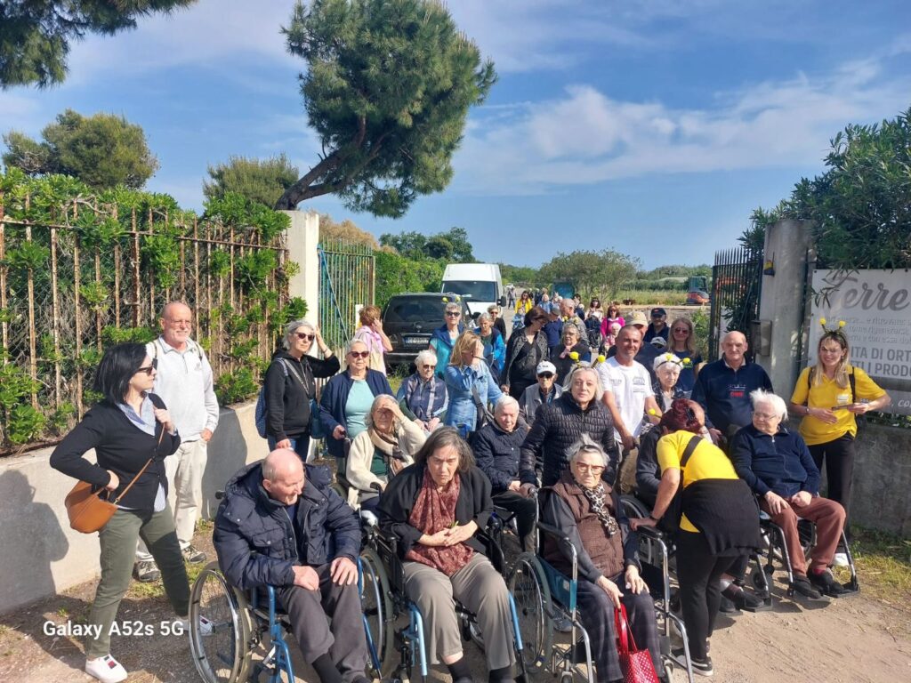 Un gruppo di nonni, alcuni in carrozzina, accolti al cancello di Terre Ritrovate